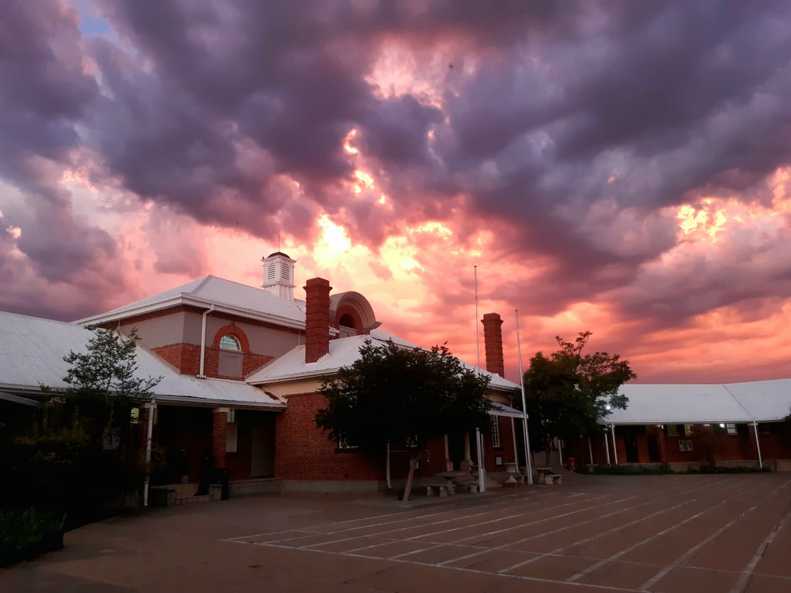 Front view of Vryburg High School main building under dramatic pink evening clouds in Vryburg, North West, South Africa.