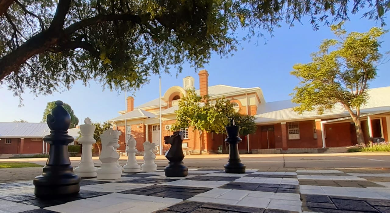 Vryburg High School main building with students playing chess in Vryburg, North West, South Africa.
